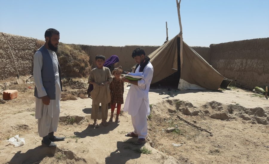 Männer mit Plänen stehen vor einem notdürftig aufgestelltem Zelt