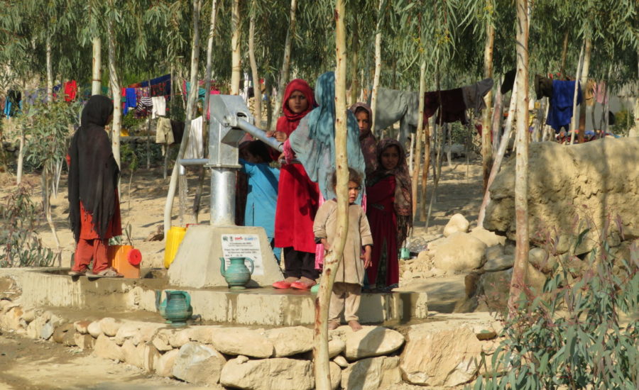 Frauen und Kinder bedienen eine Wasserpumpe in Nangarhar
