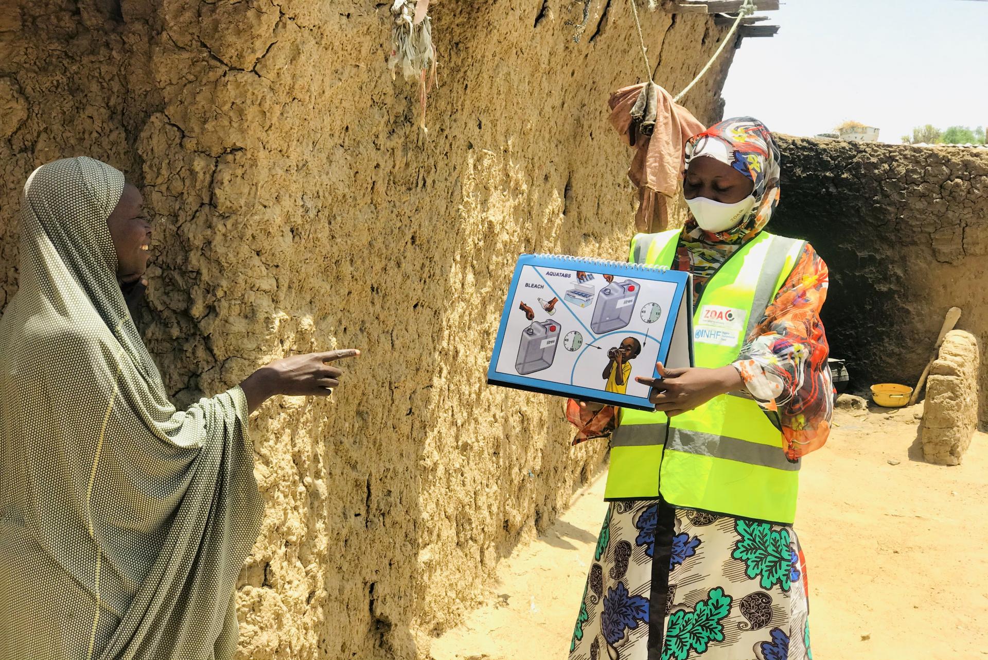 Fanne aus Nigeria schult eine Frau in Hygieneregeln