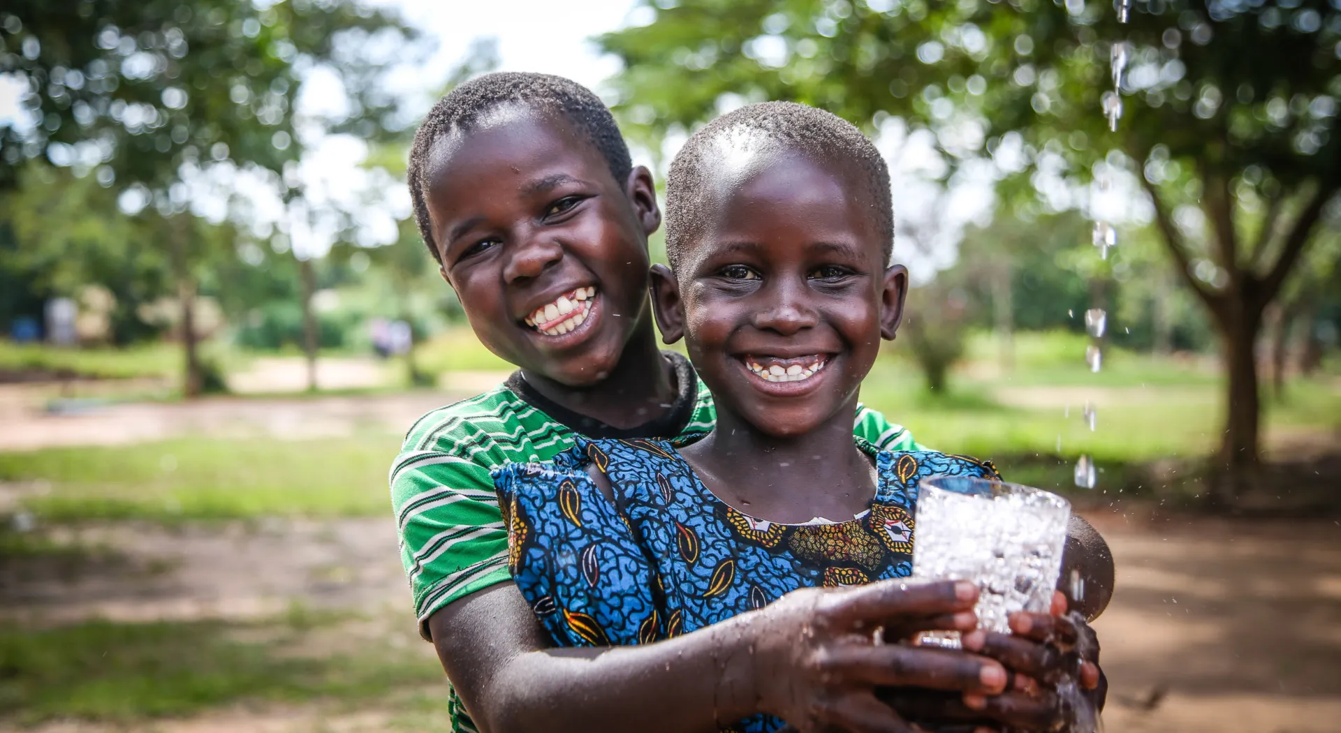 WASH: Zwei lachende Jungs halten ein Wasserglas