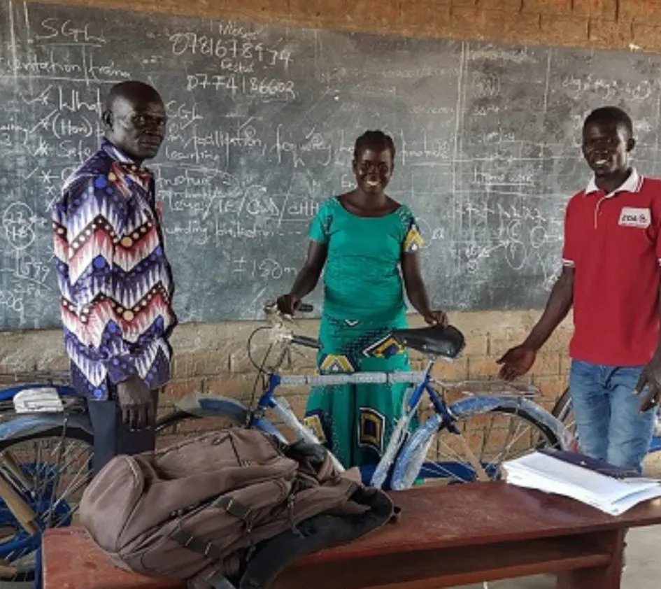 Schulunterricht: Lehrkräfte in Uganda stehen mit ihren Fahrrädern vor der Tafel