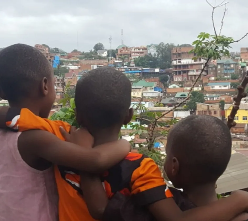 Justine: Drei Kinder umarmen sich und überblicken die Stadt