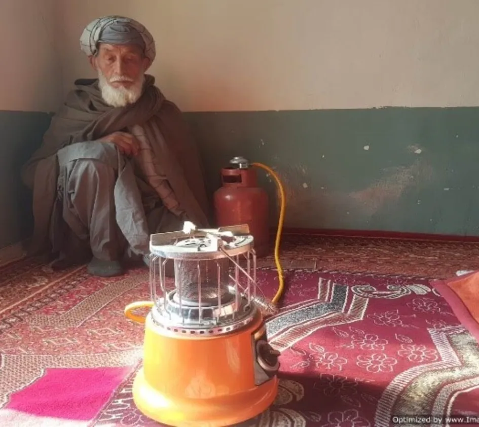 Durch den Winter: Afghanischer Mann sitzt vor einem Gaskocher