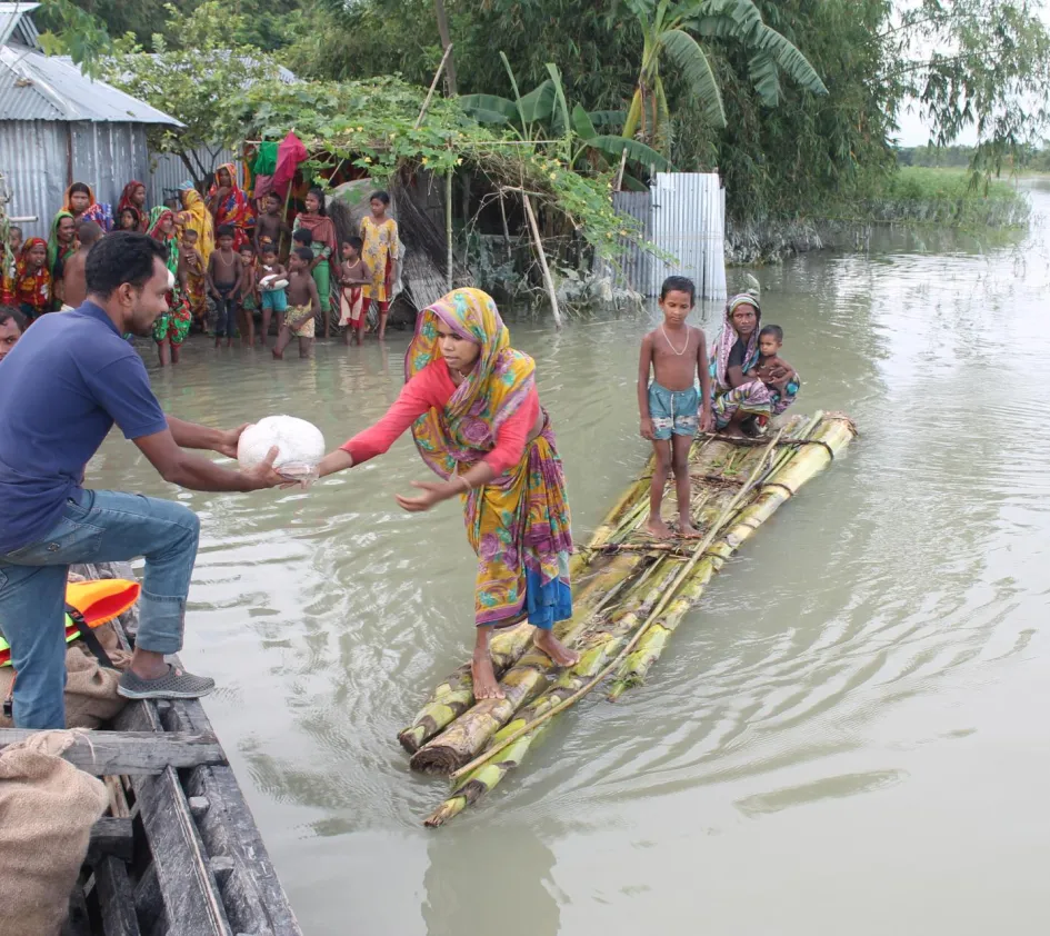 Sri Lanka: Frau auf einem Floß reicht Mann an Land Nahrung