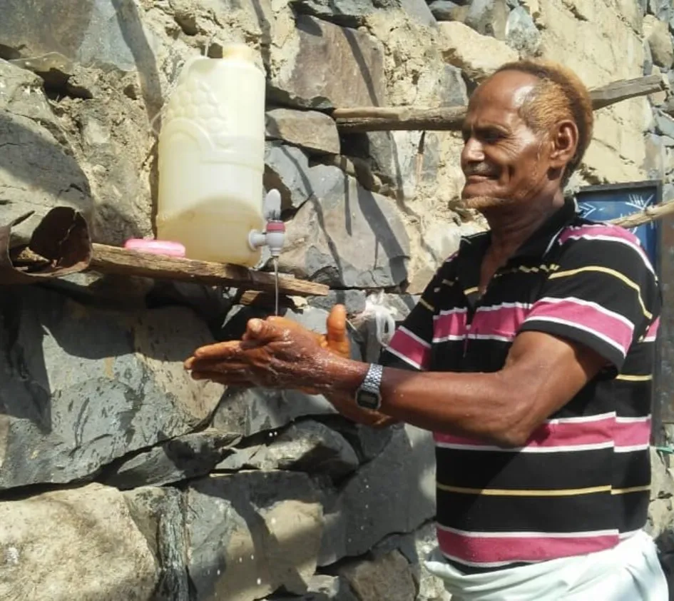 COVID-19: Mann wäscht Wasser an einem Wasserhahn