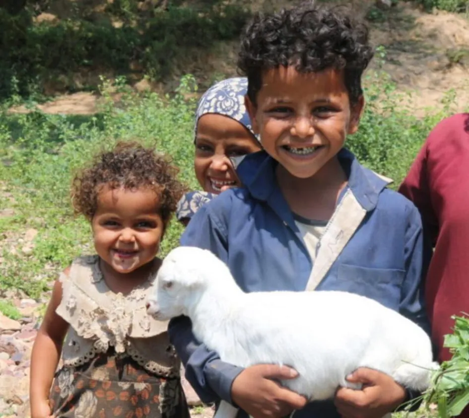 Nothilfe und Wiederaufbau: Kinder lachen und halten ein Schaf