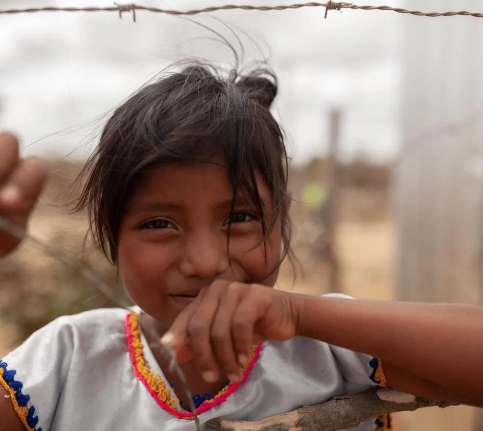 Liste der Vergessenen: Kolumbianisches Mädchen steht an einem Maschendrahtzaun