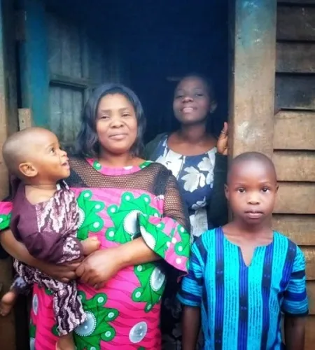 Justine mit drei ihrer Kinder vor ihrem Haus