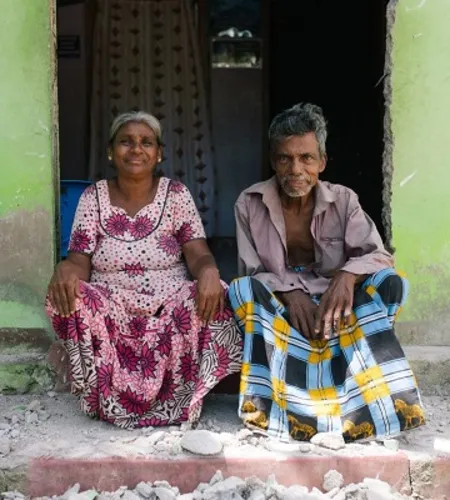 Zwei Sri Lanker sitzen vor ihrem neuen Haus