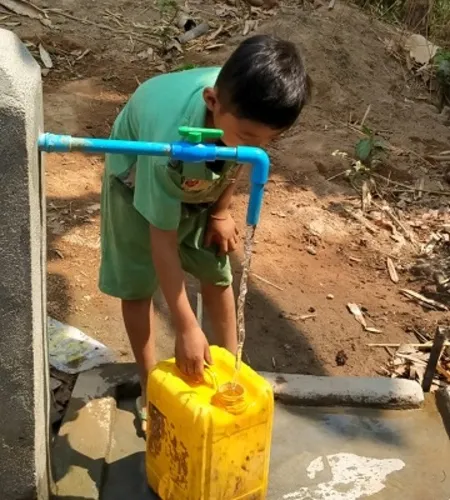 Saw Kwar Lay füllt Wasser in einen Kanister aus einem der neuen Brunnen