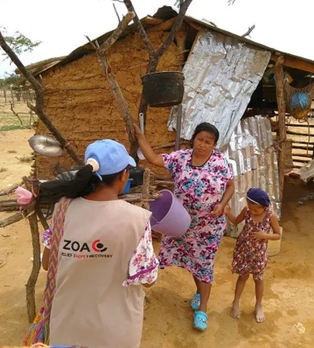 ZOA Mitarbeiterin mit venezolanischer Familie vor ihrer Holzhütte