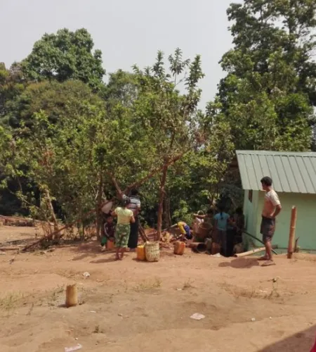 Familie mit Kindern vor einem Haus mit Wellblechdach