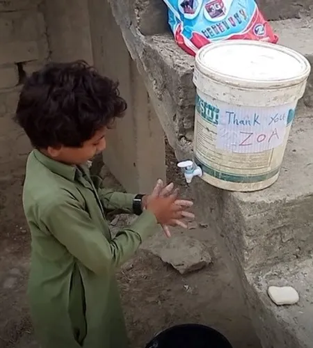 Junge wäscht die Hände an einem recycelten Wasserbehälter