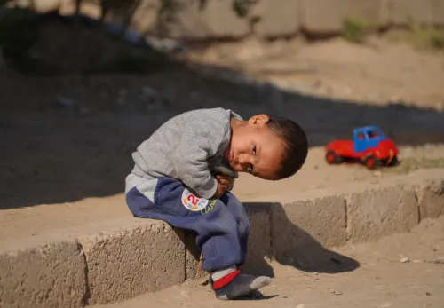 5 Fakten über Syrien: Ein Kind sitzt auf einer Bordsteinkante.
