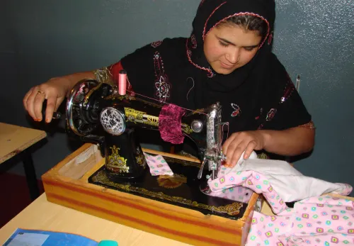 Afghanische Frau lernt das Nähen an der Nähmaschine