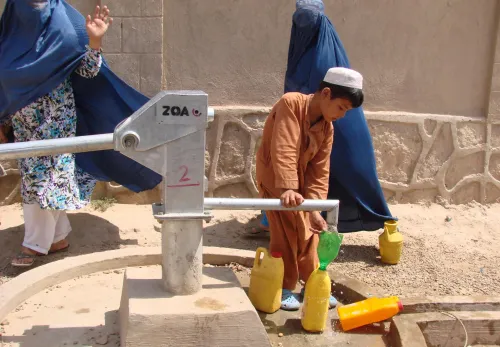 Afghanischer Junge schöpft Wasser an einer Wasserpumpe