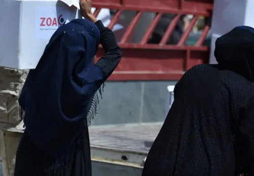 Frauenrechte in Afghanistan: Verhüllte Frau trägt ein Paket mit ZOA Aufschrift