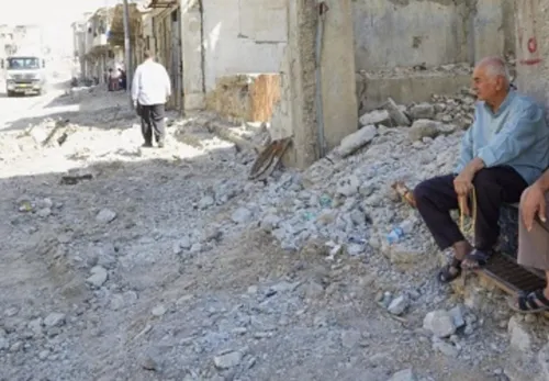 Leid: Zwei Männer sitzen auf den Stufen eines zertrümmerten Gebäudes