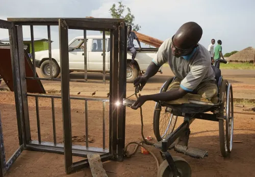 Menschen mit Beeinträchtigungen: Mann im Rollstuhl lötet Metall